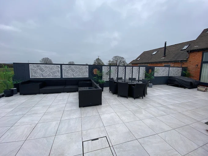 Large light grey porcelain patio with outdoor seating and privacy screens