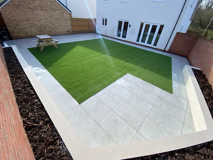 Artificial lawn framed by light porcelain paving and bark borders