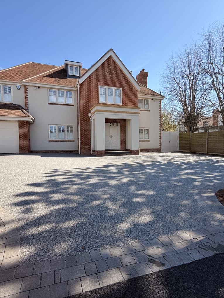 Finished resin bound driveway with a block paved border in front of a large detached house