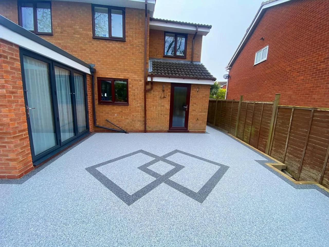 A Scandinavian Marble resin patio with a charcoal border and diamond inlay, laid by our team.