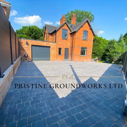 After: charcoal block paved driveway leading to a garage beside a red brick house
