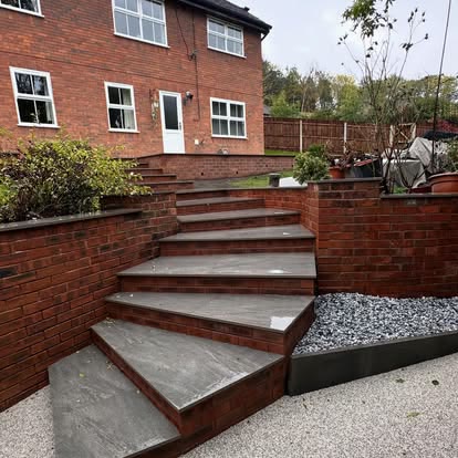 Grey stone garden steps between red brick retaining walls