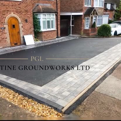 After: new tarmac driveway with a grey block border outside a house with an arched wooden door