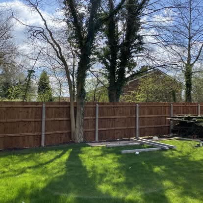 New closeboard fence along a lawn with mature trees