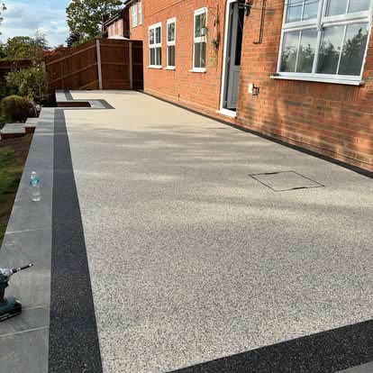 Large light resin bound patio alongside a brick house