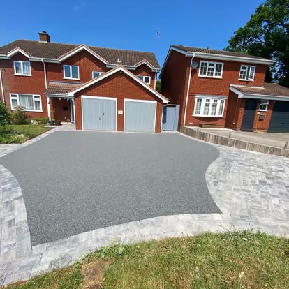 A grey resin driveway framed by a silver block border.